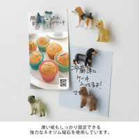 Dog-shaped magnets on a white surface with a magazine featuring cupcakes.